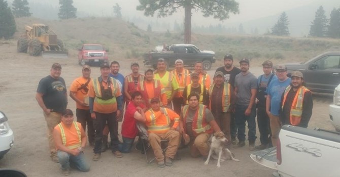 Brad Pierro (fifth in from right, wearing black shirt) and the twelve men who stayed to help fight the fire pose for a photo with some other men who came later to help keep things under control.
