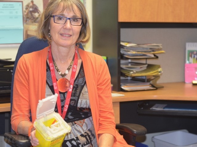 Elaine Collison, general manager of the People Place, holds a sharps container full of discarded needles picked up from around the building. 