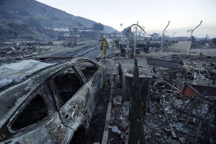 Fire crews search for hot spots among destroyed homes in the Rancho Monserate Country Club community Friday, Dec. 8, 2017, in Fallbrook, Calif. The wind-swept blazes have forced tens of thousands of evacuations and destroyed dozens of homes in Southern California.