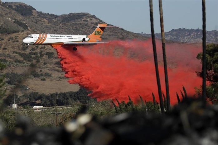 A plane drops fire retardant on a wildfire Friday, Dec. 8, 2017, in Fallbrook, Calif.