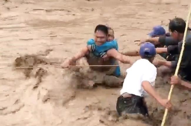 In this photo made from video by Aclimah Disumala, Friday, Dec. 22, 2017, villagers carry an elderly woman across raging flood waters in Lanao del Norte, Zamboanga Pennisula, southern Philippines. A tropical storm has unleashed flash floods and set off landslides in the southern Philippines leaving dozens of people dead.