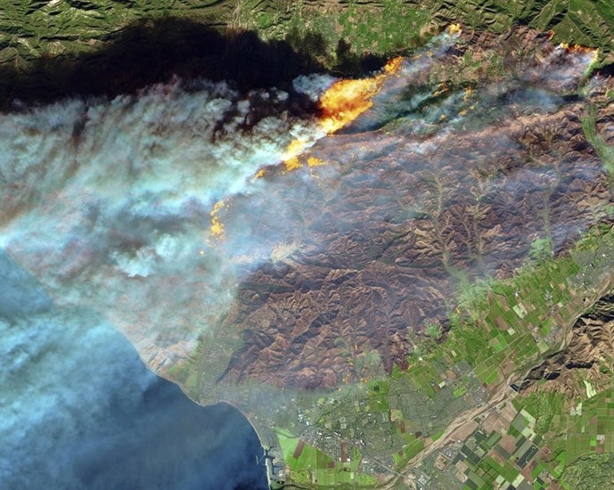 this Thursday, Dec. 7, 2017 false-color image from the European Space Agency’s Sentinel-2 satellite via NASA, shows a brown burn scar from the Thomas fire north of the city of Ventura, Calif., at bottom center. The flames stand out starkly as smoke billows toward the Pacific Ocean and untouched areas of vegetation appear in bright shades of green.