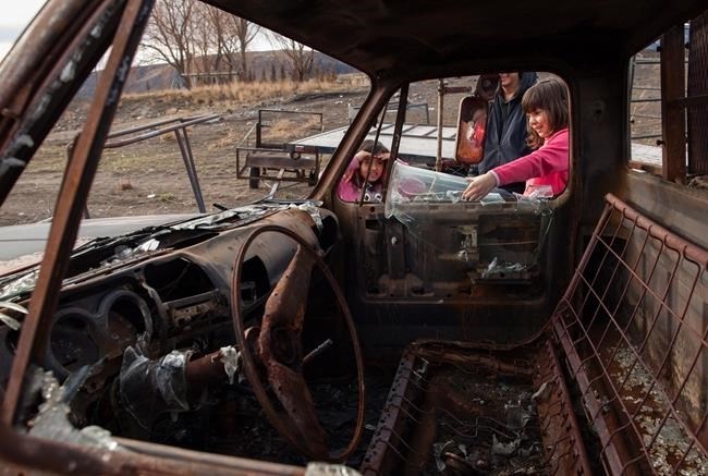 Tacheena Sutherland, 8, left, watches Nevaeh Porter, 9, look at the burned out truck at her grandparents' home in in Ashcroft, B.C., on Monday, November 27, 2017.