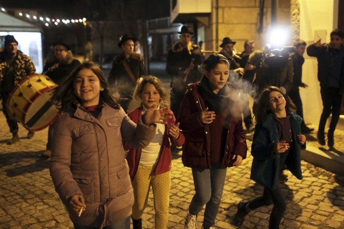 Children smoke while walking with a music band in the village of Vale de Salgueiro, northern Portugal, during the local Kings’ Feast Friday night, Jan. 5, 2018.