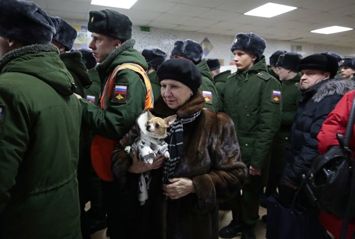 A woman with her dog lines up with Russian military personnel to vote in the presidential election in Moscow, Russia, Sunday, March 18, 2018.