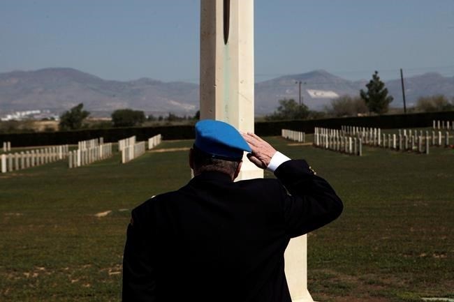 A Canadian veteran soldier who served with the United Nations Peacekeeping force on war-divided Cyprus salutes a monument dedicated to the memory of fallen British and Canadian soldiers at a cemetery inside the UN-controlled buffer zone on the outskirts of the capital Nicosia on Tuesday, March 18, 2014.