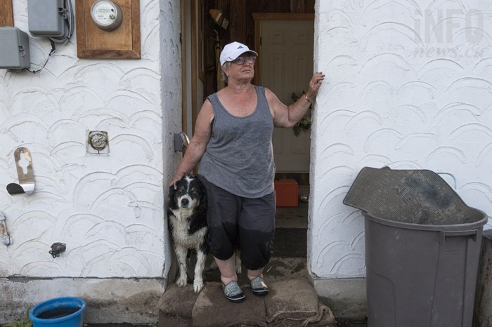 Mischelle Pierce stands with her dog Dexter on top of the sandbags they have been putting in front of their house to stop the flooding on Sunday, May 13, 2018. Pierce and her husband, Bill Pierce, are one of the households in Merritt, B.C. affected by flooding