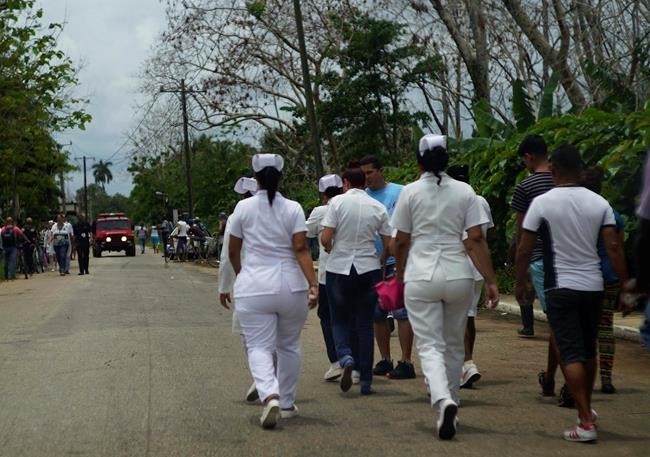 Nurses walk to the site where a Cuban airliner with more than 100 passengers on board plummeted into a yuca field just after takeoff from the international airport in Havana, Cuba, Friday, May 18, 2018.