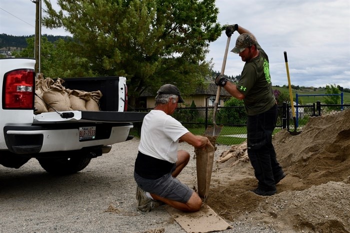 Green Bay resident Terry Balfour (left) and his son-in-law Jodie Lapointe fill sandbags at a community sand pile in West Kelowna, May 18, 2018