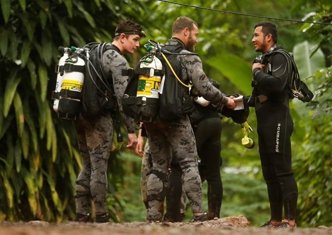 Australian Federal Police and Defense Force personnel talk to a Thai rescuer, right, before diving after the 12 boys and their soccer coach were found alive, in Mae Sai, Chiang Rai province, in northern Thailand, Tuesday, July 3, 2018.