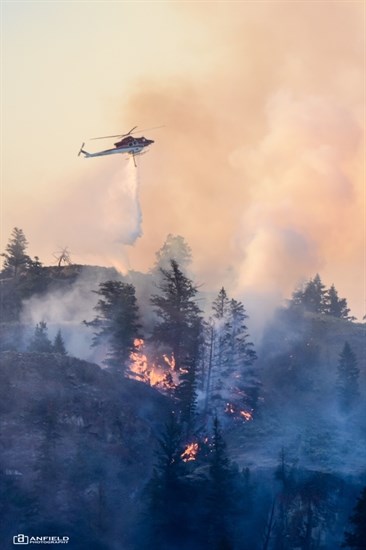 A helicopter is seen performing a bucketing operation on the East Shuswap Road wildfire in Kamloops, Friday, July 13, 2018.