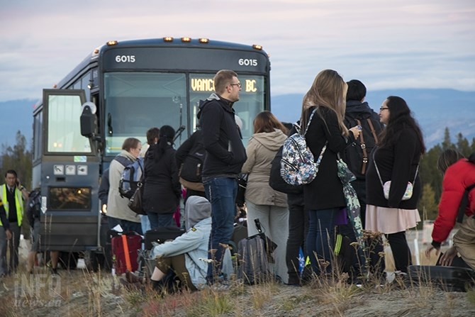 A crowd of passengers en route to Vancouver stand on the shoulder of the road. Some are calling friends and family to tell them  the bus broke down and they might be late.