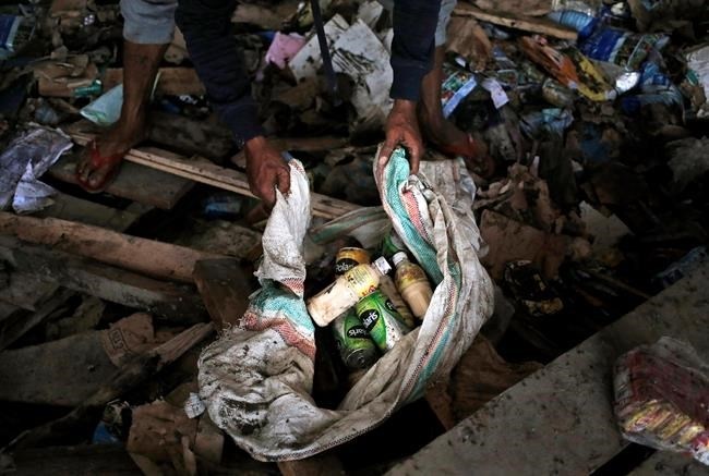 A man put beverages scavenged from an abandoned warehouse into a sack at an earthquake and tsunami-affected area in Palu, Central Sulawesi, Indonesia Indonesia, Wednesday, Oct. 3, 2018. Clamouring over the reeking pile of sodden food or staking out a patch of territory, people who had come from devastated neighborhoods and elsewhere in the remote Indonesian city pulled out small cartons of milk, soft drinks, rice, packets of sweets and painkillers from the pile as they scavenge for anything edible in the warehouse that tsunami waves had pounded.