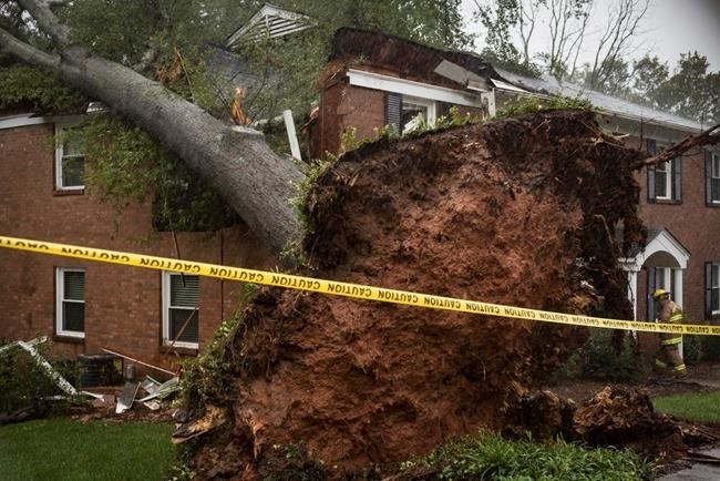 A Winston-Salem firefighter walks toward an apartment building which was struck by a toppled tree Thursday, Oct. 11, 2018, after the remnants of Hurricane Michael passed through Winston-Salem, N.C.