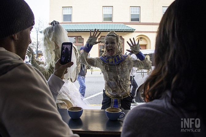 A couple of patrons at Zack's Coffee take a picture of a mummy-inspired zombie staring at them through the window.