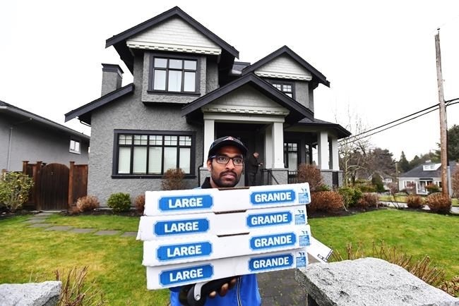 A pizza delivery man delivers pizza to the media after being instructed to do so by people inside of Huawei chief financial officer Meng Wanzhou's home in Vancouver on Wednesday, December 12, 2018.
