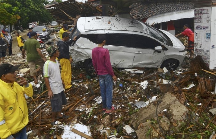 People inspect the wreckage of a car swept away by a tsunami in Carita, Indonesia, Sunday, Dec. 23, 2018. The tsunami occurred after the eruption of a volcano around Indonesia's Sunda Strait during a busy holiday weekend, sending water crashing ashore and sweeping away hotels, hundreds of houses and people attending a beach concert.