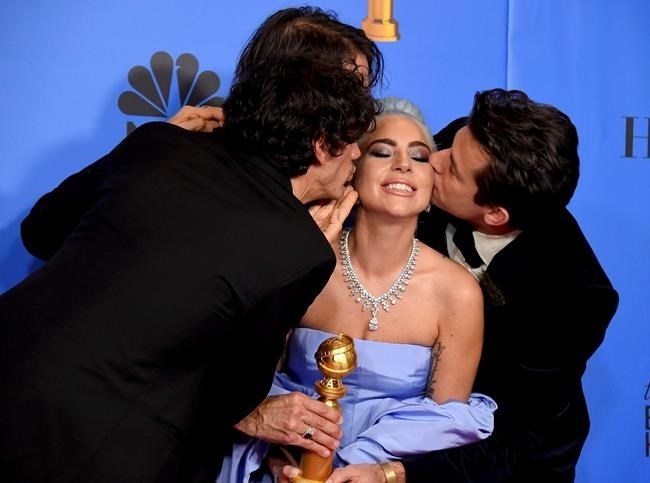 Anthony Rossomando, from left, Andrew Wyatt, and Mark Ronson, right, kiss Lady Gaga, second right, as they pose in the press room with the award for best original song, motion picture for 