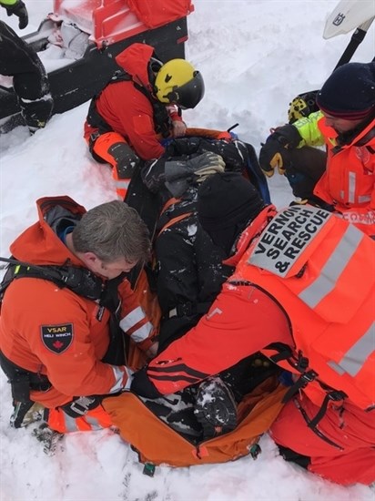 Ground search and rescue teams arrive to help secure the man to a clamshell stretcher with spinal immobilization.  He is being kept warm with a specialized stretcher package and loaded aboard the helicopter.