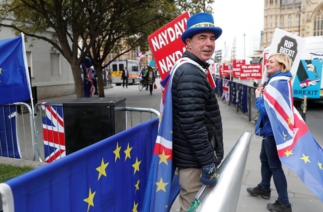 Steve Bray, an anti Brexit protester, holds onto a large megaphone as he demonstrates outside the House of Parliament in London, Tuesday, March 26, 2019. British Prime Minister Theresa May's government says Parliament's decision to take control of the stalled process of leaving the European Union underscores the need for lawmakers to approve her twice-defeated deal.