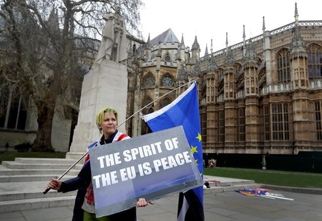 An anti Brexit campaigner holds a banner outside Parliament in London, Wednesday, March 27, 2019. British lawmakers were preparing to vote Wednesday on alternatives for leaving the European Union as they seek to end an impasse following the overwhelming defeat of the deal negotiated by Prime Minister Theresa May.