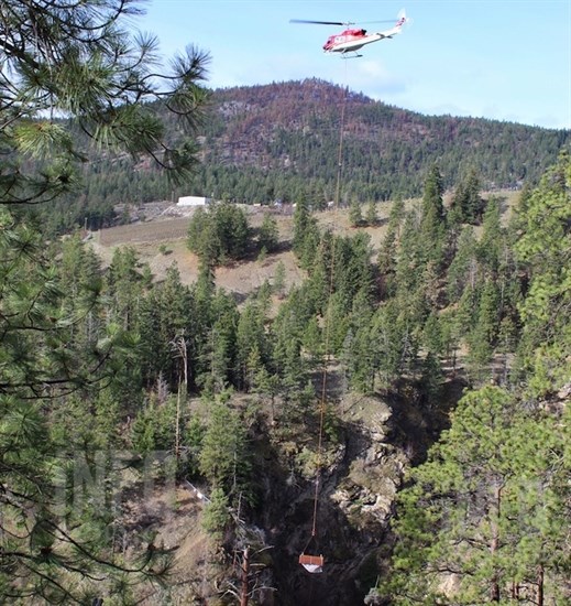 A helicopter airlifts a wooden prefabricated bridge in Hardy Falls Provincial Park, Thursday, April 11, 2019.