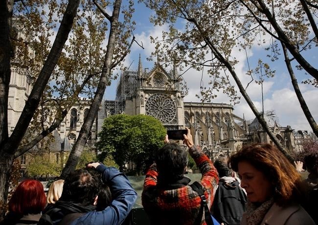 Tourists and others photograph the damage to the Notre Dame cathedral in Paris, Wednesday, April 17, 2019. Nearly $1 billion has already poured in from ordinary worshippers and high-powered magnates around the world to restore the Notre Dame cathedral in Paris after a massive fire.