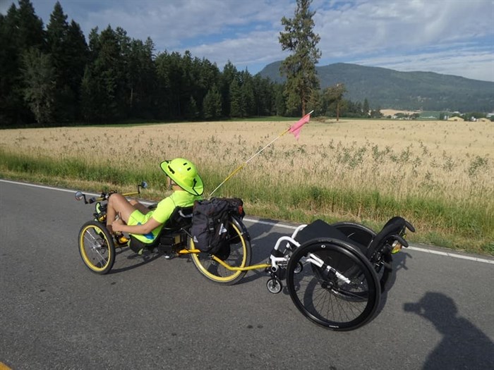 Strong tows his wheelchair behind his bike.