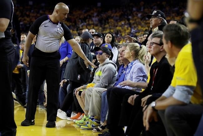 In this photo taken Wednesday, June 5, 2019, referee Marc Davis, left, gestures toward Golden State Warriors investor Mark Stevens, partially obscured in blue shirt, during the second half of Game 3 of basketball's NBA Finals between the Warriors and the Toronto Raptors in Oakland, Calif. An NBA spokesman said Thursday the conduct of Stevens at Game 3 of the NBA Finals was 