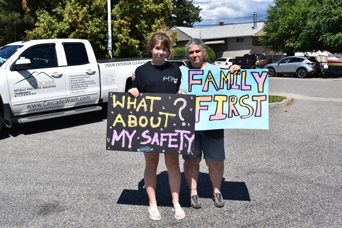Two protesters hold signs during a walking tour, Tuesday, June 25, 2019, of Kelowna's Rutland neighbourhood.