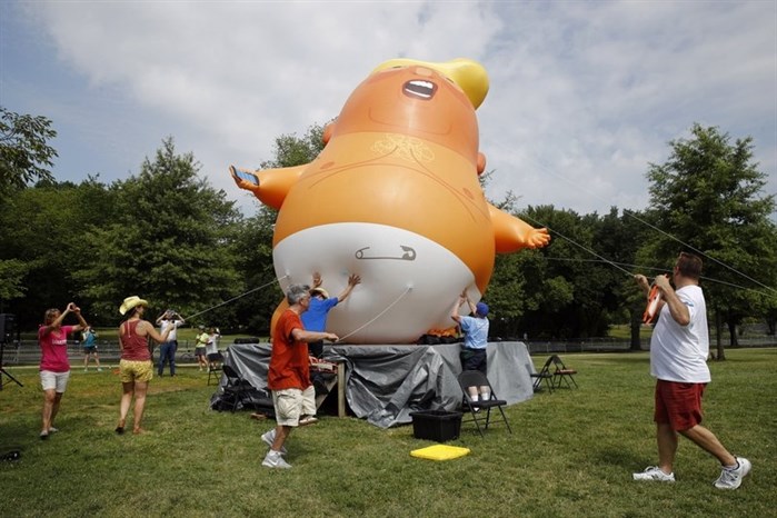 Protesters move a Baby Trump balloon into position before Independence Day celebrations, Thursday, July 4, 2019, on the National Mall in Washington. 