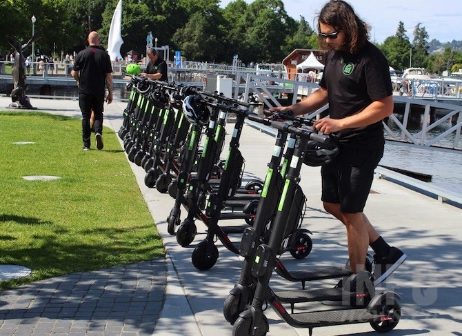 Tomy Thisdale helps set up the 25 Ogo e-scooters on display today, July 12, 2019