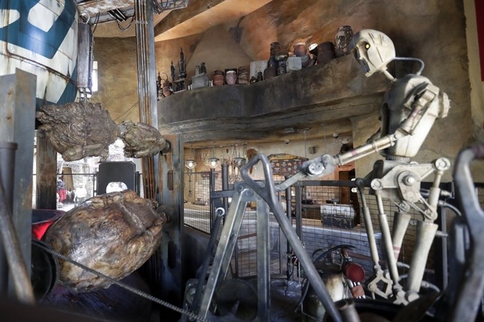 A robot cooks 'space meat' near the entrance of the Ronto Roasters restaurant during a preview of the Star Wars themed land, Galaxy's Edge in Hollywood Studios at Disney World, Tuesday, Aug. 27, 2019, in Lake Buena Vista, Fla. The attraction will open Thursday to park guests. 
