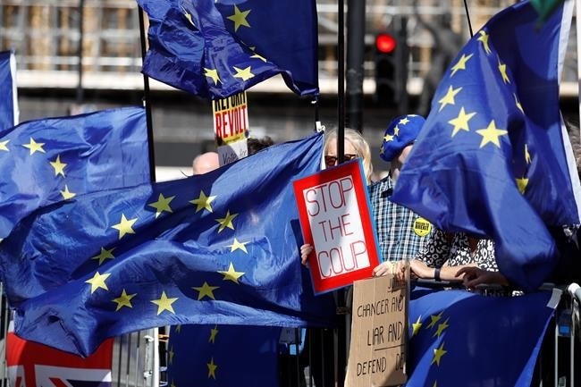 Remain supporters wave flags and hold signs during a demonstration outside the gates of Parliament in London, Wednesday, Sept. 4, 2019.