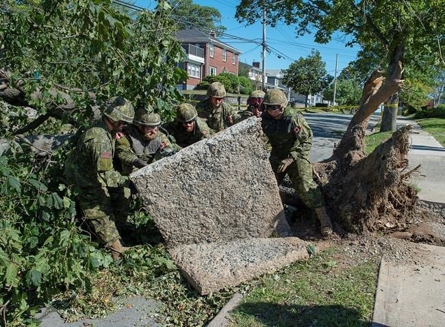 Members of the 4 Engineer Support Regiment from Canadian Forces Base Gagetown move a slab of sidewalk as they assist in the cleanup in Halifax on Monday, Sept. 9, 2019. Hurricane Dorian brought wind, rain and heavy seas that knocked out power across the region.