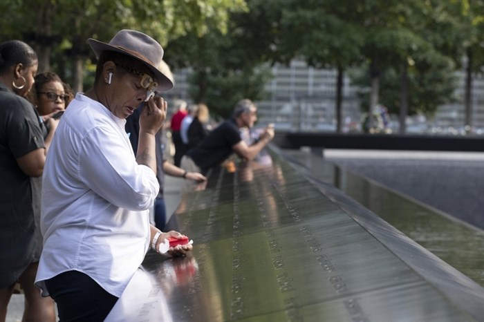 A woman wipes away tears as she stands next to the north pool prior to a ceremony marking the 18th anniversary of the attacks of Sept. 11, 2001 at the National September 11 Memorial, Wednesday, Sept. 11, 2019 in New York. 