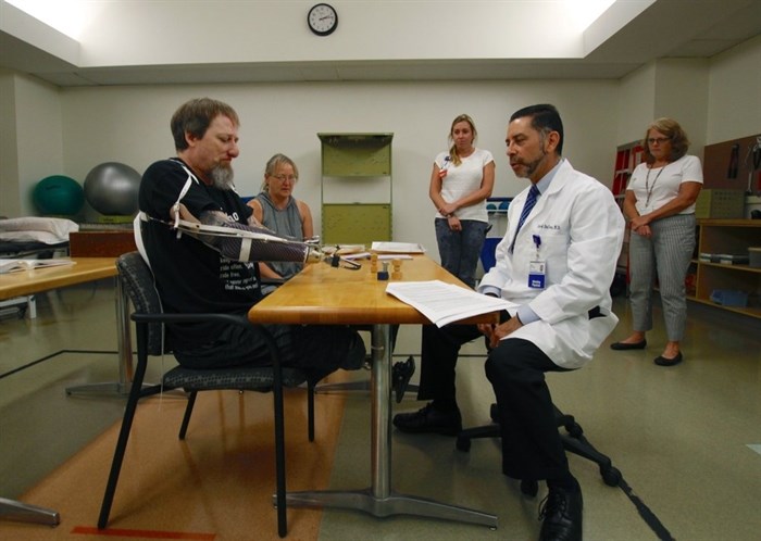 In this Aug. 19, 2019 photo, Greg Manteufel tries out a new prosthetic arm during occupational therapy at Froedtert & the Medical College of Wisconsin in Milwaukee, as he talks to Dr. David Del Toro, the medical director for inpatient rehab.