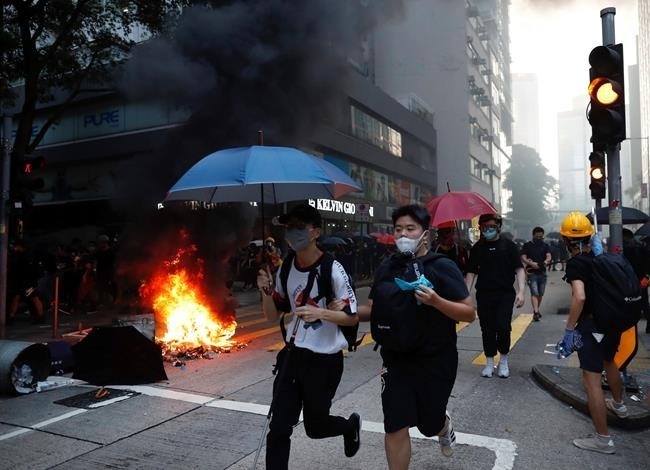 People run as police use tear gas to disperse anti-government protesters in Hong Kong, Tuesday, Oct. 1, 2019. Thousands of black-clad protesters marched in central Hong Kong as part of multiple pro-democracy rallies Tuesday urging China's Communist Party to 
