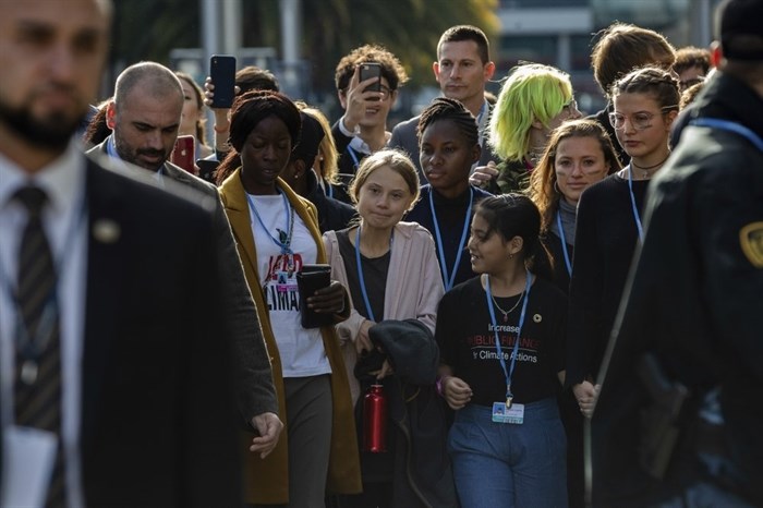 Climate activist Greta Thunberg, center and left, walks at the COP25 climate talks summit in Madrid, Friday, Dec. 6, 2019. Thunberg arrived in Madrid Friday to join thousands of other young people in a march to demand world leaders take real action against climate change. 