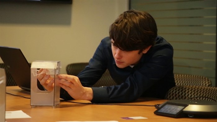 A UBC Okanagan engineering student studies a model of a clothing donation bin.