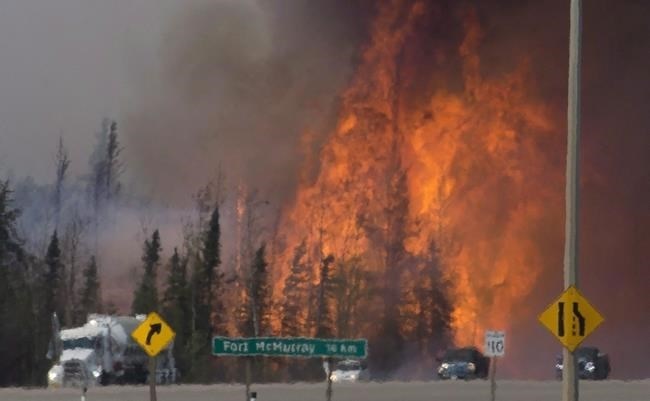 Heat waves are seen as cars and trucks try and get past a wild fire 16km south of Fort McMurray on Highway 63, Friday, May 6, 2016. The Fort McMurray fire is among Canada's biggest wildfires in the last two decades.