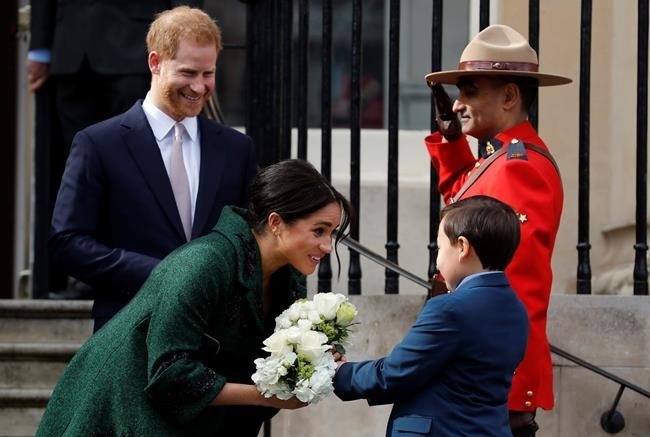 FILE - In this Monday, March 11, 2019 file photo Britain's Prince Harry and Meghan, Duchess of Sussex, receive a bouquet of flowers from two children as they leave the Canadian High Commission following a visit on Commonwealth Day in London. In a stunning declaration, Britain's Prince Harry and his wife, Meghan, said they are planning 