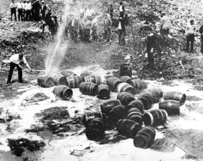 FILE - In this June 18, 1931, file photo beer barrels are destroyed by prohibition agents at a dump in New York City. The federal government, as well as state and local authorities, spent huge sums on enforcement yet never allocated sufficient resources to do the job effectively. Bootleggers awash in cash bribed judges, politicians and law enforcement officers to let their operations continue. 