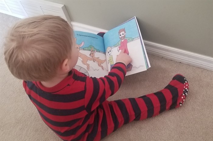 Heidi Chirkoff's son, Connor, who is now 18 months old is pictured reading his mom's published book, He'll Be Home Soon.
