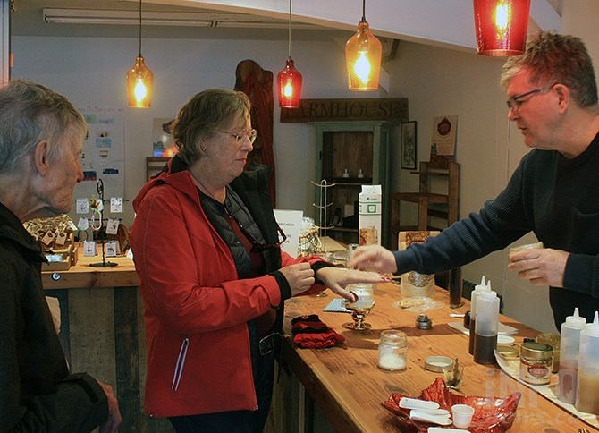 Summerland's  Roch Fortin shows Diane McArthur of Toronto some of the maple products in his Maple Roch store in Summerland, while Shirley McArthur of Vernon looks on.