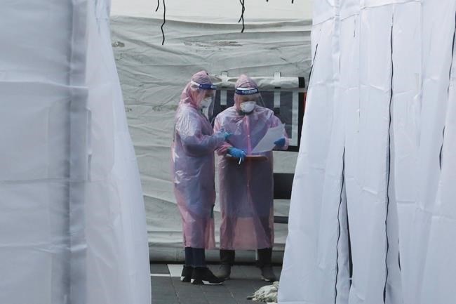 Medical staff wearing protective suits check documents as they wait for people with suspected symptoms of the new coronavirus, at a testing facility in Seoul, South Korea, Wednesday, March 4, 2020. Drive-thru clinics testing people for COVID-19 in South Korea could serve as a model for Canada, where the spread of the virus is comparatively limited but increasing to the point that such early interventions could be considered, an epidemiologist says.