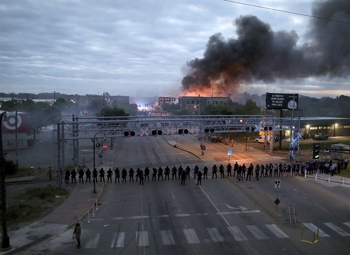 Law enforcement officers amassed along Lake Street near Hiawatha Ave. as fires burned after a night of unrest and protests in the death of George Floyd early Friday, May 29, 2020 in Minneapolis. Floyd died after being restrained by Minneapolis police officers on Memorial Day. 