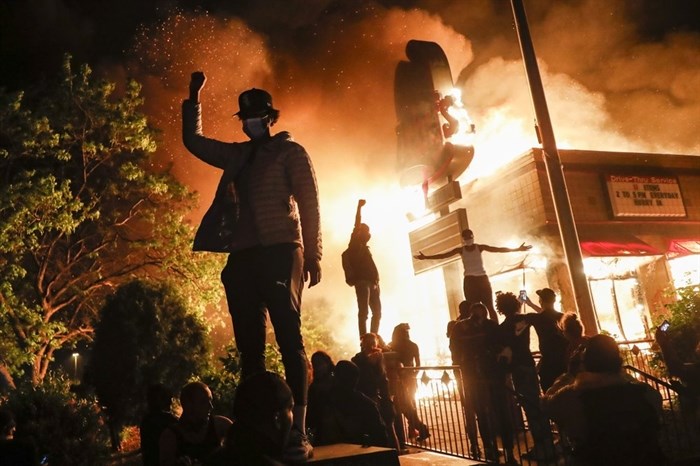 Protestors demonstrate outside of a burning fast food restaurant, Friday, May 29, 2020, in Minneapolis. Protests over the death of George Floyd, a black man who died in police custody Monday, broke out in Minneapolis for a third straight night. 