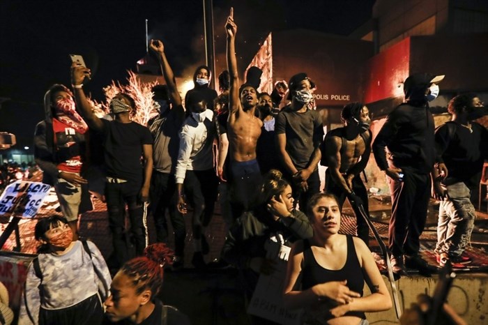 Protestors demonstrate outside of a burning Minneapolis 3rd Police Precinct, Thursday, May 28, 2020, in Minneapolis. Protests over the death of George Floyd, a black man who died in police custody Monday, broke out in Minneapolis for a third straight night. 