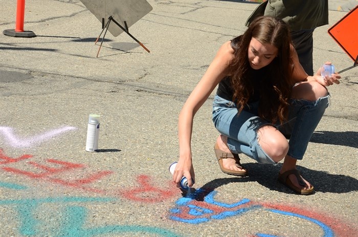 Valedictorian Neave Allen paints her name on Suicide Hill.